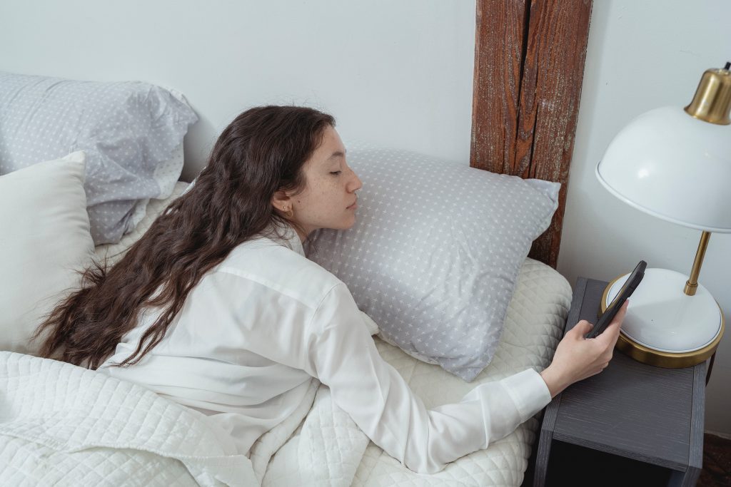 woman using her phone on bed